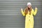 A long-haired stylish girl in a yellow coat and hat smiles and shows her fingers up thumbs up