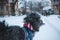 Long-haired tibetan terrier dog dressed in jacket walking in snowfall weather. Winter walk