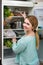 Long-haired woman arranging space in fridge at home