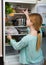 Long-haired woman arranging space in fridge at home