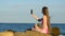 Long-haired young woman sitting on the beach with an ice cream and take pictures on the phone