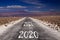 Long hard stony way concept: view on endless dirt road through dry desert with numbers of years 2020, 2021, 2022