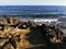 Long-hardened lava, porous, sharp coast of the Mediterranean Sea with oncoming waves against a skys