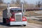 Long haul 18 wheeler semi truck hauling freight driving on road with diesel train and boxcars in background.