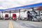 Long haulers big rigs semi trucks with semi trailers fuel tanks with diesel standing on the gas station on the truck stop