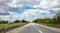 Long highway in the american countryside, blue cloudy sky background