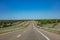 Long highway in the american countryside, blue cloudy sky background