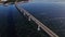 Long highway bridge over a frozen river with clear cracked ice and traffic driving by.