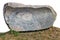 Long horizontal monument of rough red  granite stone lie on grass isolated