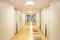 Long hospital corridor with light walls  colorful floor and ceiling with plafone lamps illuminated. Health care and medical backgr