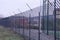 Long iron green fence of twigs and barbed wire on the street