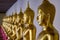 A long line of gilded statues of seated Buddhas at Buddhist temple