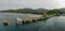 Long loading pier with rusted and equipment stretches into sea on coast