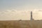 Long, low angle shot of lighthouse beyond bokeh effect sand