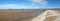 Long panoramic view of southport pier from the beach with blue shy reflected in water on the beach at low tide