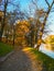 Long path in small park next to city moat and small hill with glimpses of the sun