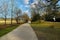 A long paved bike trail with a yellow line in the middle with a woman running in a red top and lush green trees