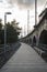 Long paved path beside the arches of a viaduct under a cloudy sky