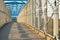 A long pedestrian tunnel with metal mesh design. Aerial pedestrian crossing over the highway, perspective goes to the horizon.