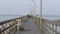 Long peir along the water with seagulls flying and people walking and fishing