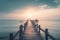 a long pier extending into the ocean at sunset with a boat in the distance