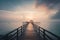 a long pier stretches out into the ocean at sunset with a gazebo in the distance