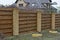 long private brown fence on a rural street made of wooden boards and bricks