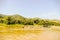 Long public boat on dirty lake water with dense overgrown foliage on the shoreline in a jungle