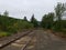 Long railroad track and pebbles or stones and green trees