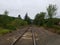 Long railroad track and pebbles or stones and green trees