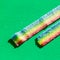 Long rainbow colored marmalade candy. Versicolor marmalade in the sugar on the green background. Copy space