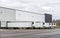 Long refrigerator semi trailers stand in row in warehouse docks with gates and loading cargo