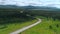 A long road with cars. The view from the drone. Scene. A bright summer landscape with seedy mountains and forest in the