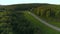 A long road with cars. The view from the drone. Scene. A bright summer landscape with seedy mountains and forest in the