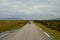 Long road throug flat landscape with mountain and fog in backdrop