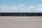 Long row of black garbage containers outside under the blue sky with white clouds