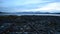 Long rusted metal boat landing ramp leading out into blue fjord with mountain