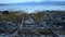 Long rusted metal boat landing ramp leading out into blue fjord with mountain