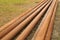 Long rusty pipes in meadow beside construction site