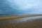 Long sandy beach of Norfolk coast and low dark blue cloudy sky, Northern Sea, Holkham beach, United Kingdom
