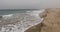 A long sandy beach with sand dunes entering the sea