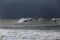 Long sea wave against rainy sky