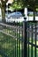 Long section of tall wrought iron fencing with pointed tops following the property lines of home on busy street