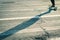 Long shadow of a skateboarder cruising through crosswalk