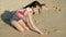 Long shot of cheerful girl drawing cloud in sand on beach