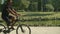 Long shot of focused man with prosthetic leg riding bike in park