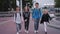 Long shot of four pupils with backpacks going out of school and talking
