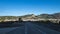 Long single lane empty street during sunrise with mountains and the city in the background