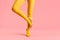 Long slim legs of young woman in yellow tights and high heels shoes balance on one foot