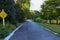 A long smooth footpath in the park with a family sitting on a park bench on a stone bridge over a lake